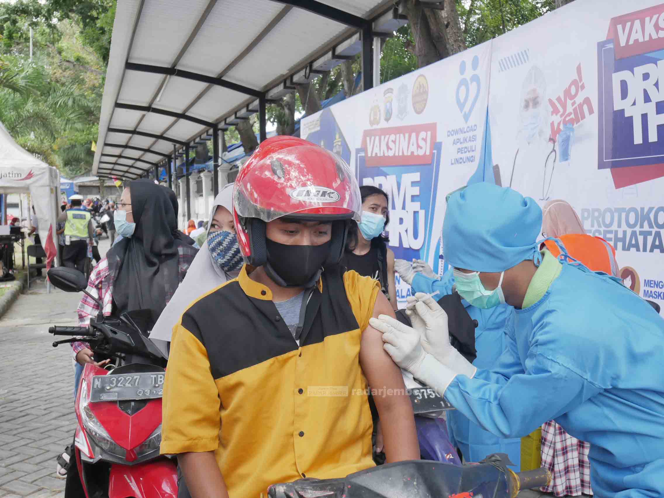 PRAKTIS: Sejumlah warga menerima suntikan vaksin di pos vaksinasi drive thru Stadion Semeru Lumajang. Proses vaksinasi tersebut dinilai praktis karena warga cukup duduk di atas kendaraan bermotor, lalu disuntik.