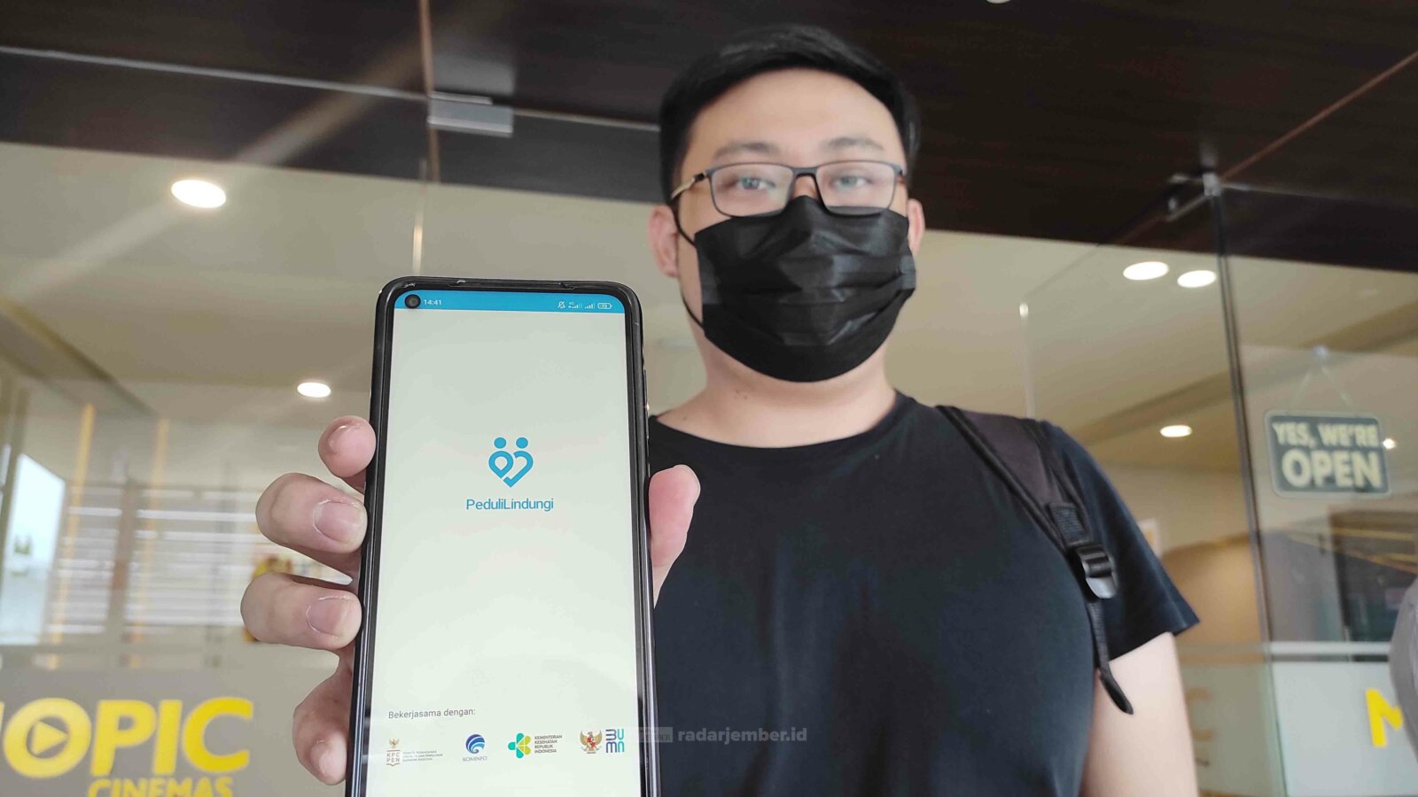 TEGAS: Salah seorang pengunjung bioskop menggunakan aplikasi PeduliLindungi sebelum memasuki bioskop Mopic Cinemas, kemarin. Bioskop ini merupakan tempat pertama yang menerapkan aturan PeduliLindungi di Lumajang.