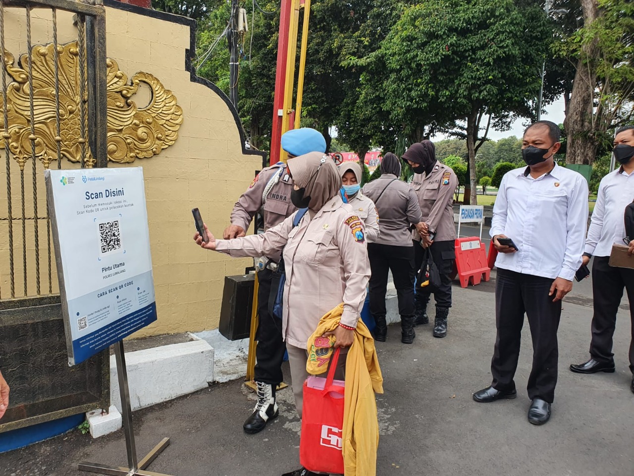 MULAI BERLAKU: Sejumlah anggota Kepolisian Resor (Polres) Lumajang melakukan scan barcode aplikasi PeduliLindungi sebelum memasuki mapolres, kemarin. Mulai awal pekan ini, hal tersebut mulai diberlakukan.