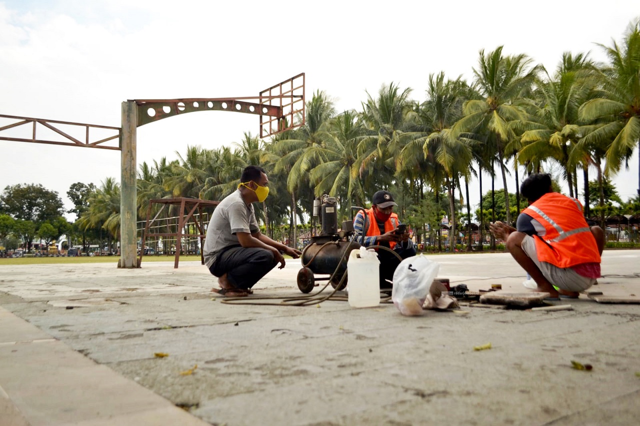 DIBENAHI: Lapangan basket di Alun-Alun Jember ini mulai diperbaiki. Hari ini, para pekerja mulai melakukan pengecatan setelah kemarin selesai melakukan pembenahan lantai.