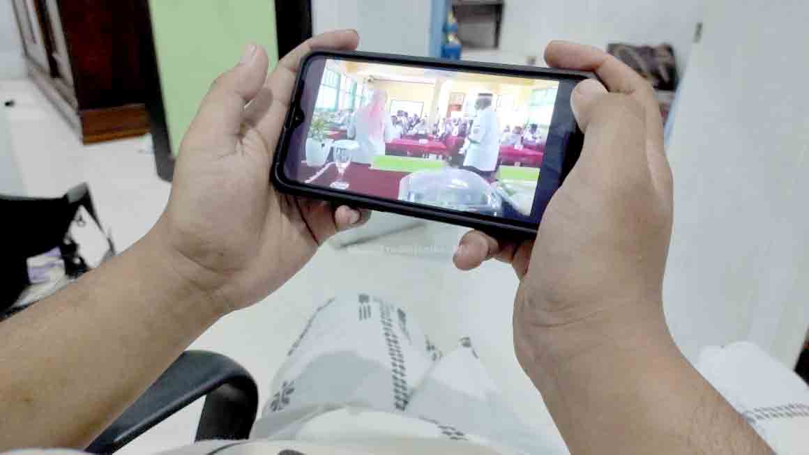 MIRIS: Salah seorang warga ketika menyaksikan video pria diduga Kepala Dinas Pendidikan dan Kebudayaan Bondowoso Sugiono Eksantoso saat menyanyi dangdut bersama wanita. Video itu tersebar luas di masyarakat, bahkan viral hingga ke luar daerah.
