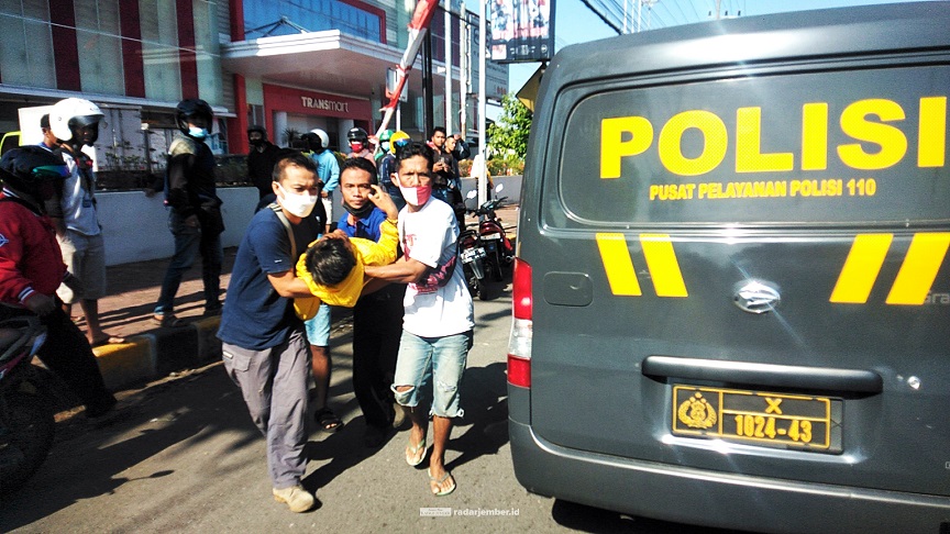 PROSES EVAKUASI: Warga dan pengguna jalan menolong korban yang tidak sadarkan diri. Dua pengendara motor yang terlibat kecelakaan itu sama-sama dibawa ke RS Kaliwates.