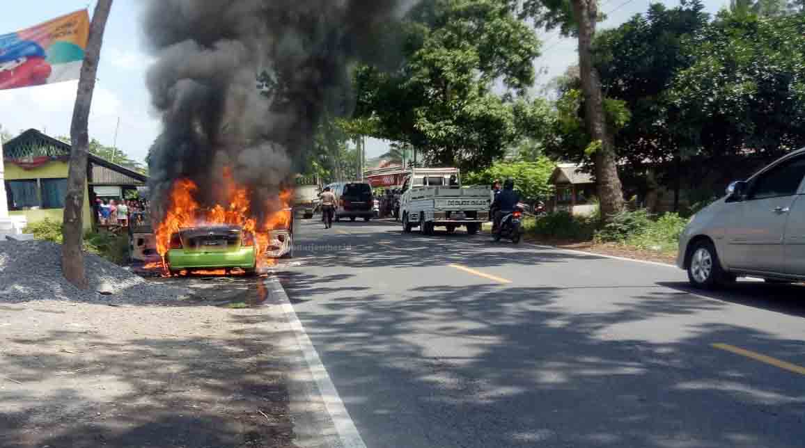 TERBAKAR: Mobil sedan milik Paimo yang terbakar di pinggir jalan nasional, Desa Wonorejo, Kecamatan Kedungjajang. Mobil itu terbakar sekitar pukul 11.00. Diduga mobil itu terbakar karena terjadi korsleting listrik.