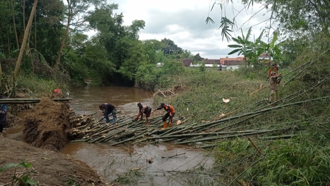 GOTONG ROYONG: Personel gabungan memotong batang bambu yang terkikis aliran di Sungai Curah Menjangan, perbatasan Desa Selokbesuki dan Kutorenon, Kecamatan Sukodono, kemarin.
