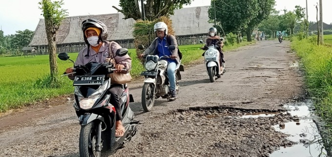 BAHAYA: Pengendara sepeda motor melewati jalan dengan kondisi rusak parah di Desa Lengkong, Kecamatan Mumbulsari. Jika tidak berhati-hati, pengendara bisa terjatuh karena terperosok ke lubang jalan.