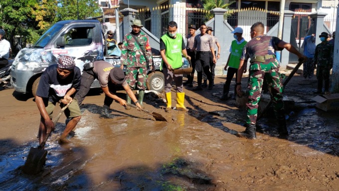BERLUMPUR: Jalan di kawasan Perumahan Bumi Mangli Permai Kecamatan Kaliwates penuh dengan lumpur sisa banjir bandang yang terjadi, Minggu (9/1) sore. Aparat TNI, polisi dan relawan BPBD membantu warga membersihkannya.