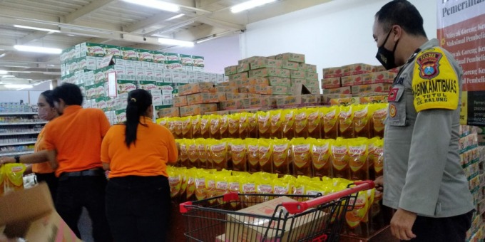 PANTAU LANGSUNG: Anggota Polsek Balung mengecek stok minyak goreng di toko ritel. Selama terjadinya kelangkaan, kepolisian terus berkoordinasi tentang ketersediaan minyak goreng dengan manajemen toko ritel maupun swalayan berjaringan.