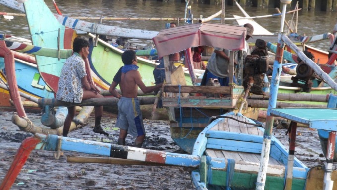 KERJA KERAS: Warga memperbaiki perahu dan jaring sebelum berangkat melaut di Pantai Puger, kemarin.