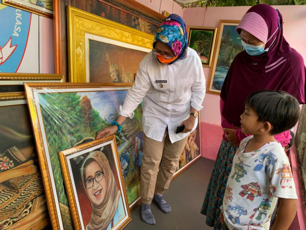 DIAPRESIASI: Wakil Bupati Lumajang Indah Amperawati (kiri) membeli lukisan wajah hasil karya Sumiati di bengkel lukisan miliknya.