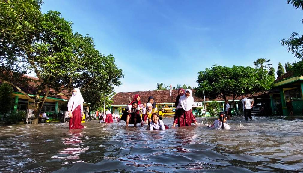 SEKOLAH DILIBURKAN: Sejumlah siswa SDN Wonojati 01, Kecamatan Jenggawah, bermain di genangan air yang membanjiri halaman sekolah mereka, Sesala (22/3).