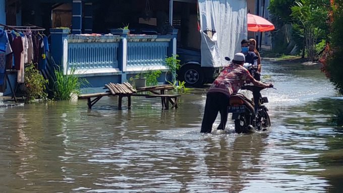SUSAH LEWAT: Warga Perumahan Griya Wonojati Indah, Kecamatan Jenggawah, kesusahan keluar masuk perumahan karena banjir.