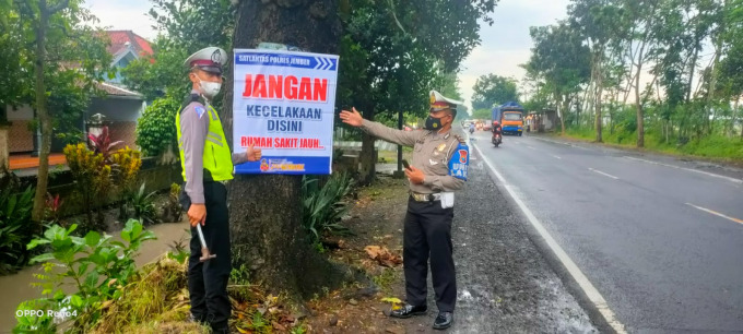 SAMPAIKAN PESAN: Personel Satlantas Polres Jember memasang banner imbauan di jalur rawan. Total ada 39 banner yang telah terpasang.