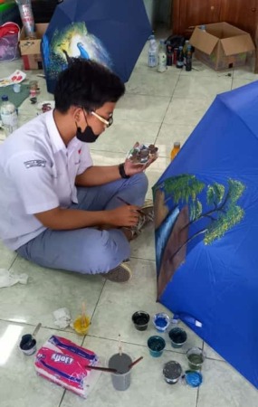 Muhammad Ilham Choiri terlahir memiliki keterbatasan, namun demikian pelajar tuna rungu tersebut pandai melukis di atas payung