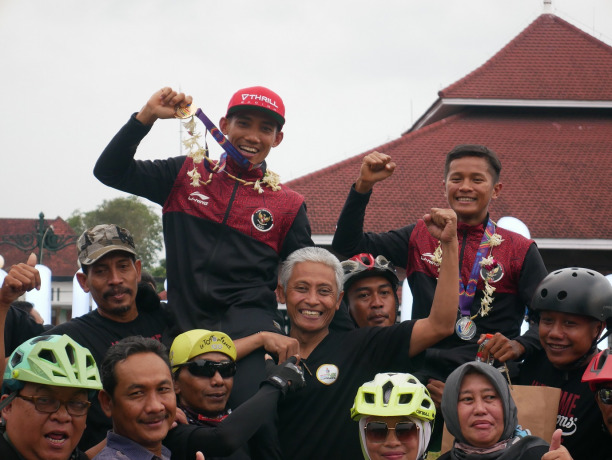 JUARA: Peraih medali emas dan perak MTB Cross Country SEA Games Vietnam Zaenal Fanani dan Ihza Muhammad saat dipanggul pencinta sepeda Lumajang saat tiba di Lumajang, Sabtu lalu (21/5).