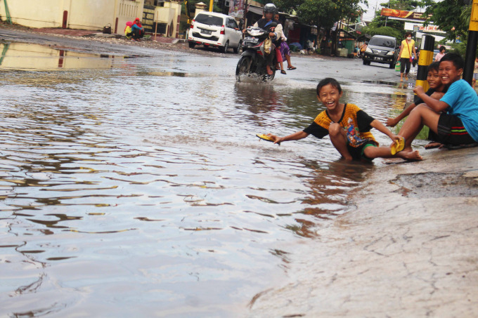SERU: Terlihat saat tiga bocah kegirangan bermain genangan air.