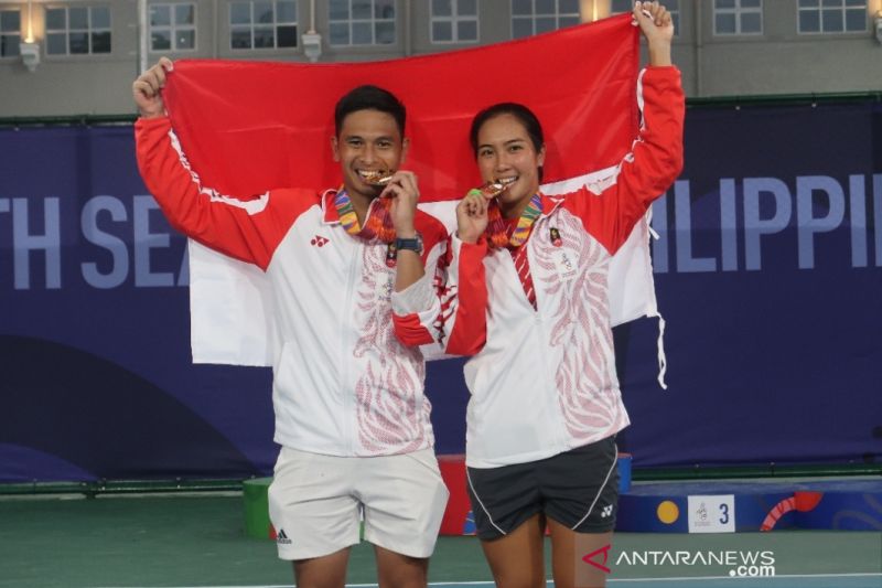 Caption Foto : Foto arsip - Pasangan ganda campuran Indonesia Christopher Rungkat (kiri) dan Aldila Sutjiadi menggigit medali emas tenis SEA Games 2019 di Kompleks Olahraga Rizal Memorial, Manila, Filipina, Sabtu (7/12/2019). Mereka menjadi yang terbaik s