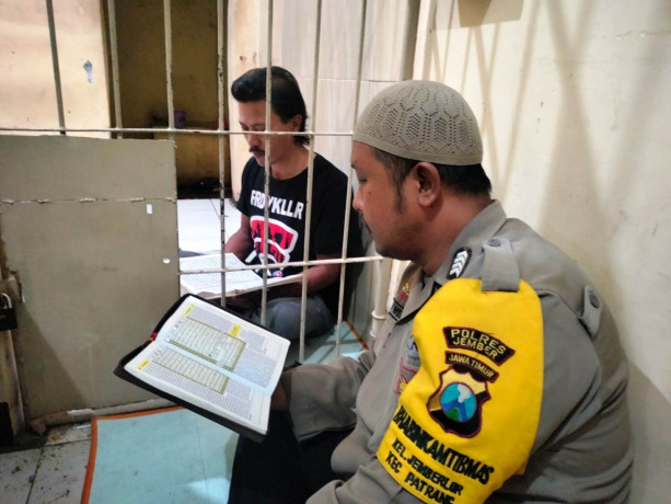 KHUSUK: Anggota SPKT Polsek Patrang Bripka Bayu Wibisono mengaji bersama Busan, seorang tahanan di polsek setempat.