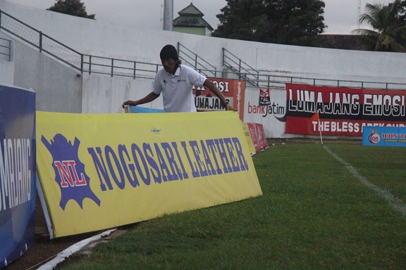 DILEPAS: Salah satu petugas saat mencopot salah satu nameboard dari lapangan Stadion Semeru. Menurutnya, regulasi yang tidak jelas tersebut merugikan dirinya sebagai salah satu sponsorship yang punya kontribusi besar.