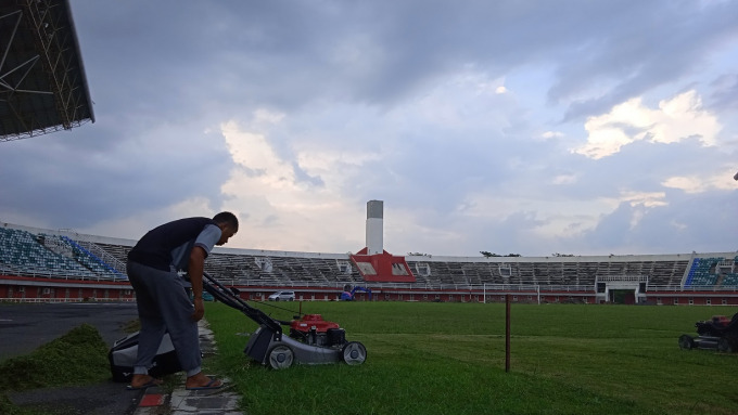 BERDAMPAK KE LAGA SEPAK BOLA: Sejumlah pegawai merawat rumput di JSG. Di sisi lain, lintasan atletik JSG yang belum selesai bisa berdampak pada pindahnya pertandingan perdana cabor sepak bola yang direncanakan pada 17 Juni mendatang.