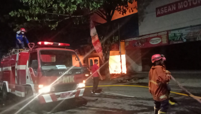 BERKOBAR: Petugas berupaya memadamkan api yang membakar bengkel Trijaya Motor daerah perempatan Mangli, Kaliwates, Jember.