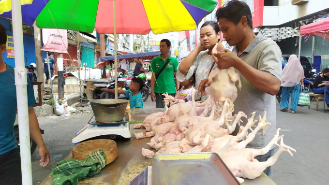 BERTRANSAKSI: Abdul Hasyim, pedagang dading ayam, saat melayani konsumen yang sedang membeli di lapaknya, Pasar Tanjung, kemarin (10/7).