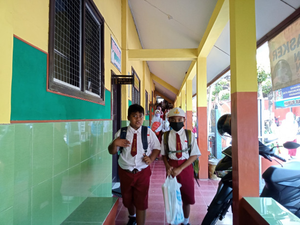 MULAI SEKOLAH: Dua siswa SDN Kebonsari 1 sedang membawa buku pendamping pelajaran yang telah diberikan di hari pertama masuk sekolah, kemarin (18/7).