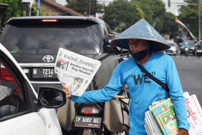 PEJUANG RUPIAH: Ahmad Wahyudi menawarkan koran Jawa Pos Radar Jember di Perempatan Karangrejo, Kecamatan Sumbersari, Jember, kemarin (15/7).