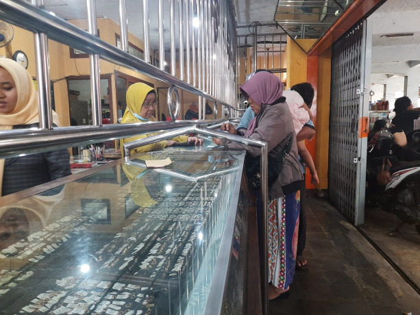 BANYAK PEMBELI: Salah seorang pembeli ketika melihat perhiasan emas di salah satu toko, Pasar Tanjung. Kini, harga emas berangsur stabil.