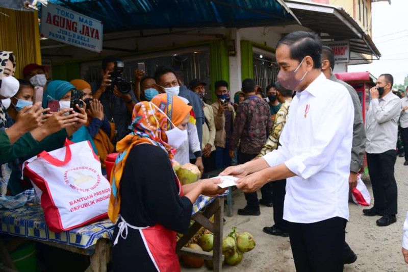 Caption Foto :  Presiden Joko Widodo menyerahkan bantuan kepada pedagang di Pasar Sukamandi, Subang, Jawa Barat, Selasa (12/7/2022).