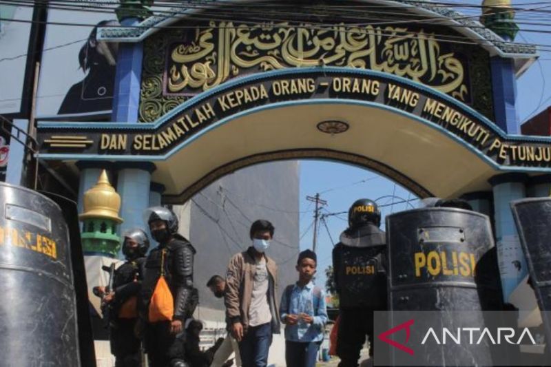 Caption Foto :  Polisi berjaga di depan gerbang Pondok Pesantren Shiddiqiyyah Ploso selama proses penangkapan Moch Subchi Azal Tsani (MSAT), orang yang diduga melakukan kekerasan seksual kepada santri, di Kabupaten Jombang, Jawa Timur, Kamis (7/7/2022).