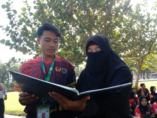 TERKEJUT: Siswa SMAN 2 Jember sekaligus atlet drum band Jember, Muhammad Ihsan Maulana, bersama ibunya melihat rapor setelah menerima medali emas di Alun-Alun Jember, kemarin.   