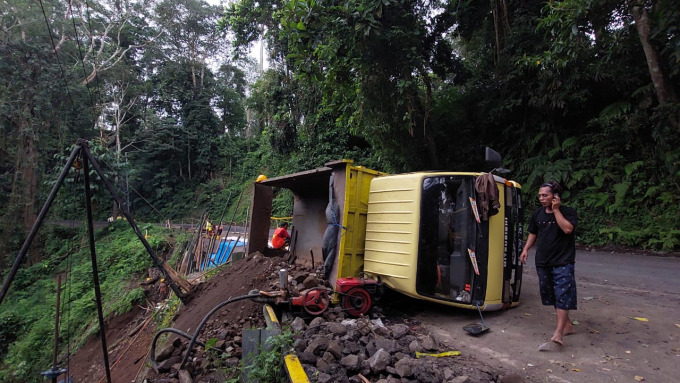KECELAKAAN KERJA: Truk pengangkut material yang terguling di jalur longsor Gumitir. Seorang pekerja terluka akibat tertimpa batu.