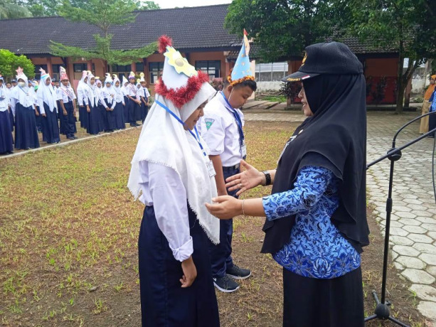 MASA PENGENALAN: Kepala SMPN 03 Bangsalsari Hermin Agustini menyematkan tanda peserta MPLS kepada siswa baru.