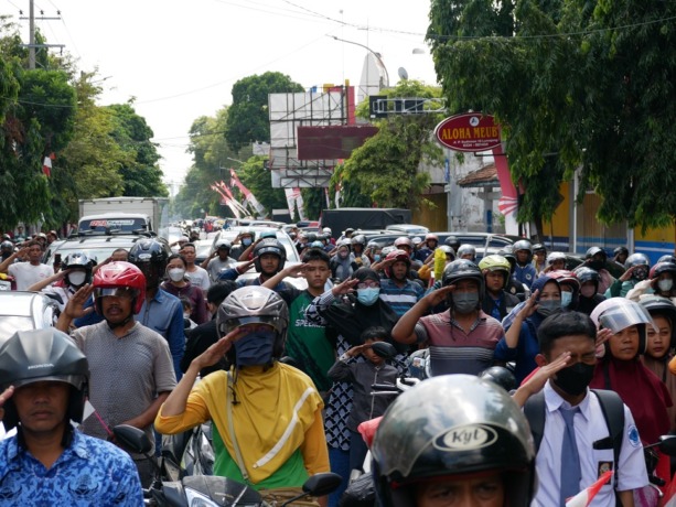 PENGHORMATAN: Sejumlah pengguna jalan di Perempatan Adipura, Tompokersan, menghentikan aktivitasnya sementara. Mereka berdiri dan memberi hormat ke bendera merah putih selama tiga menit dalam upacara, kemarin.