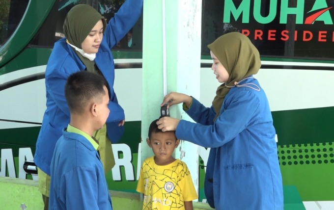 DAMPINGI MASYARAKAT: Mahasiswa Fikes Unmuh Jember tengah monitoring tinggi badan anak di Kantor Desa Kemuning Lor, Kecamatan Arjasa, Rabu, 13 Juli lalu.