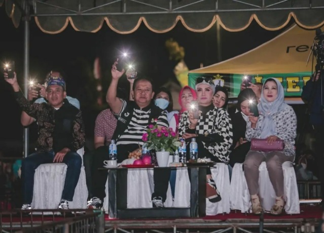 ASYIK MENONTON: Bupati Jember Hendy Siswanto bersama Ketua TP PKK Jember Kasih Fajarini ikut bersenandung saat menyaksikan Farel Prayoga bernyanyi dalam acara konser malam puncak pekan raya, Minggu kemarin (28/8), di Desa Glagahwero, Kalisat.