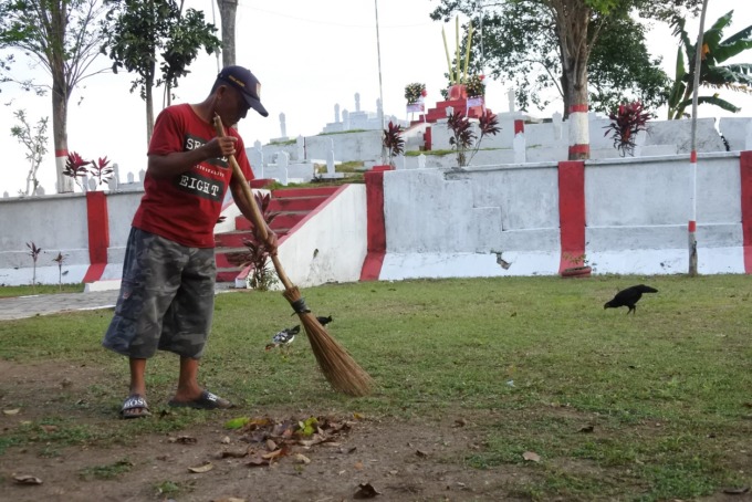 MENGABDI: Adi Priytanto, sukarelawan, menyapu TMP Ambulu, kemarin.