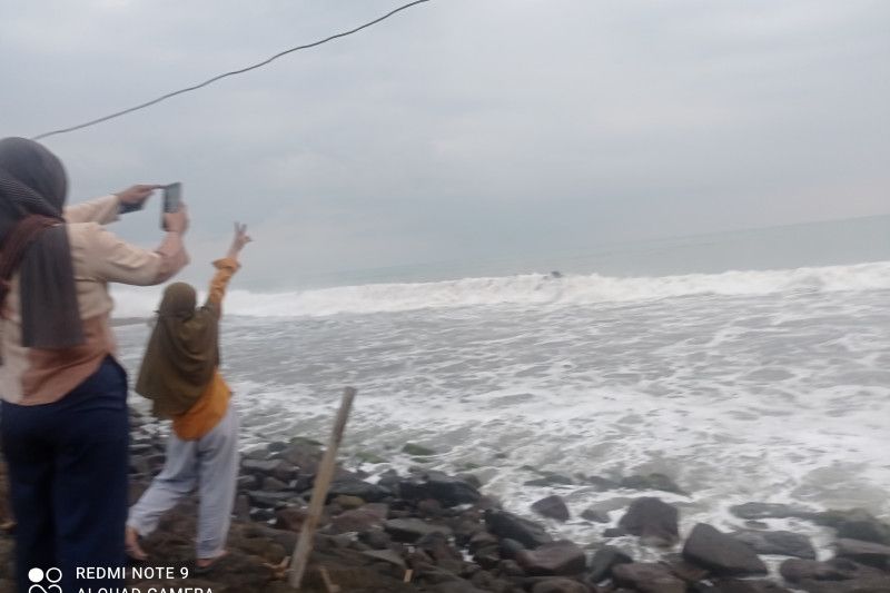 Caption Foto : Wisatawan di pesisir Pantai Anyer Kabupaten Serang, Provinsi Banten melihat kawasan Gunung Anak Krakatau yang berada di Perairan Selat Sunda yang tertutup kabut.