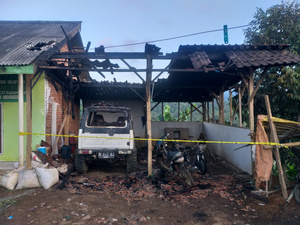 HANCUR: Petugas memasang garis polisi di lokasi perusakan rumah dan pembakaran mobil di Desa Mulyorejo, Kecamatan Silo, Jember.