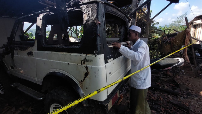 RUSAK BERAT: Petugas memasang garis polisi di garasi milik M Kosim. Korban pembakaran kendaraan di Dusun Dampik Rejo, Desa Mulyorejo, Kecamatan Silo, Jember.