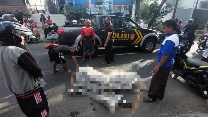 MENGENASKAN: Polisi dibantu warga mengevakuasi korban yang meninggal tertabrak truk kontainer di Jalan Merak, Patrang, Jember, Jumat (26/8) pagi.