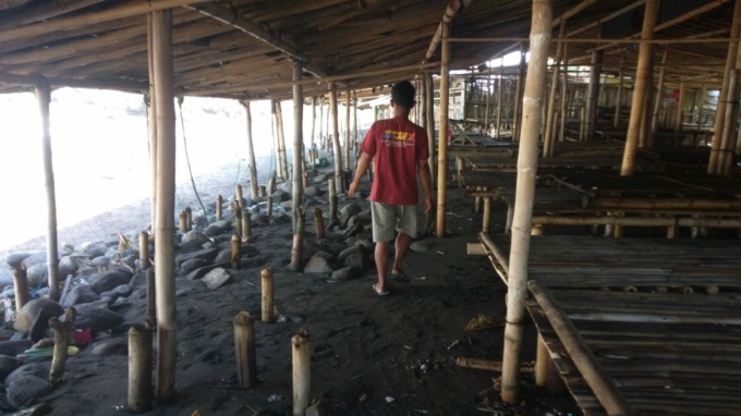 TERDAMPAK: Salah seorang pedagang di Pantai Payangan, Ambulu, Jember, mengecek kondisi warungnya setelah terkena hantaman gelombang pasang, kemarin.