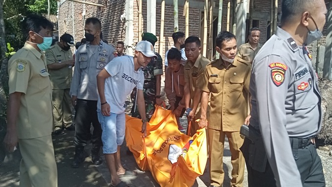 EVAKUASI: Para petugas dari kepolisian sedang mengangkat jenazah yang ditemukan meninggal di pinggir lahan padi Desa Dawuhan, Kecamatan Tenggarang, Bondowoso.