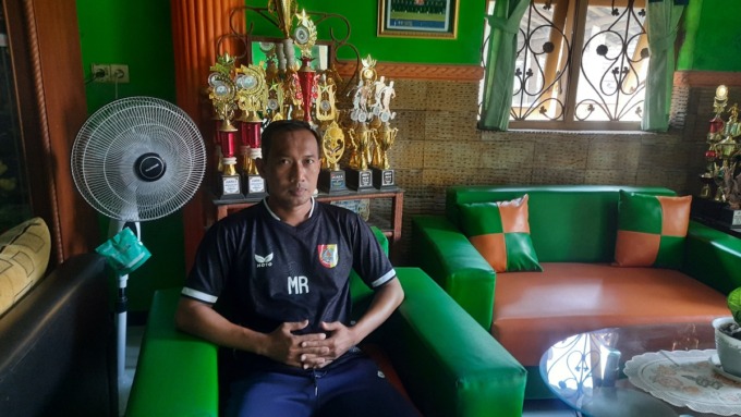 BERSANTAI: Muhammad Rofiq, pelatih sepak bola, saat di rumahnya, Desa Curah Malang, kemarin.