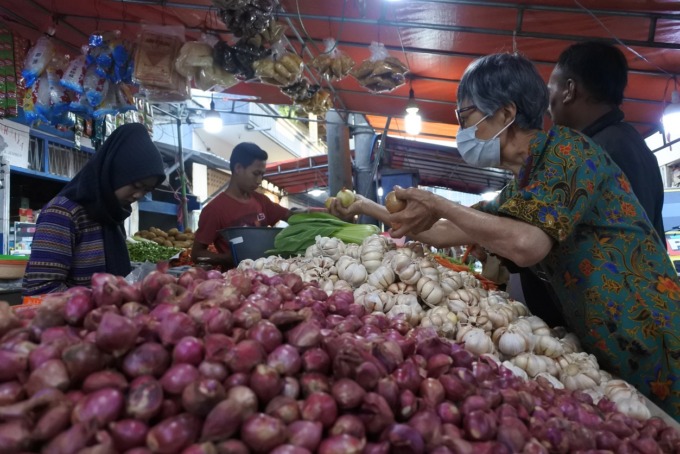 LAYANI PEMBELI: Salah seorang pedagang sayur di Pasar Tanjung ketika melayani pembeli. Pascakenaikan BBM, bahan pokok masih stabil.