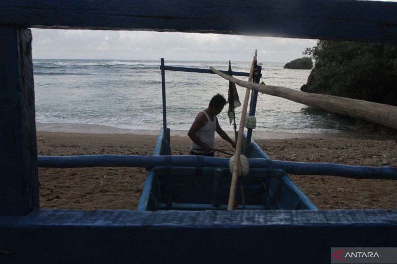 Caption Foto :  Seorang nelayan membersihkan perahu miliknya di pantai Kondangmerak, Malang, Jawa Timur, Sabtu (24/9/2022).