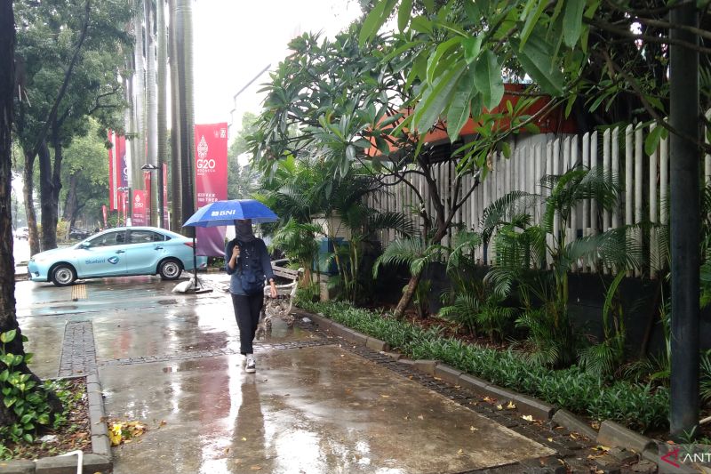 Arsip Foto - Warga berjalan menggunakan payung saat hujan turun di Jakarta.