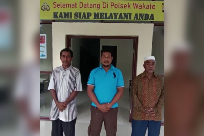 Caption Foto :  Pelaku penyalahgunaan bendera merah putih (di tengah), didampingi Kepala Dusun (kiri), dan Imam Tamhelu (kanan), melakukan permohonan maaf di depan kantor Polsubsektor Wakate, Selasa.
