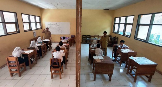 DIBAGI DUA: Siswa kelas VII dan kelas VIII SMPN 5 Silo, belajar dengan menempati ruangan yang disekat menggunakan triplek.