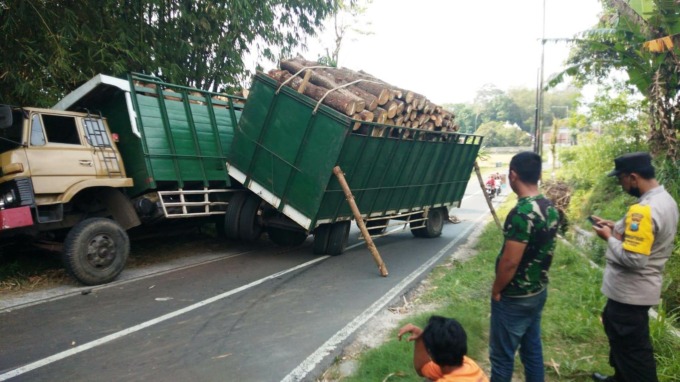 TUTUP JALAN: Truk gandeng bermuatan kayu pinus yang mengalami kecelakaan di jalan tanjakan Dusun Kramat, Desa Sebanen, Kecamatan Kalisat, Jember, Kamis (29/9).